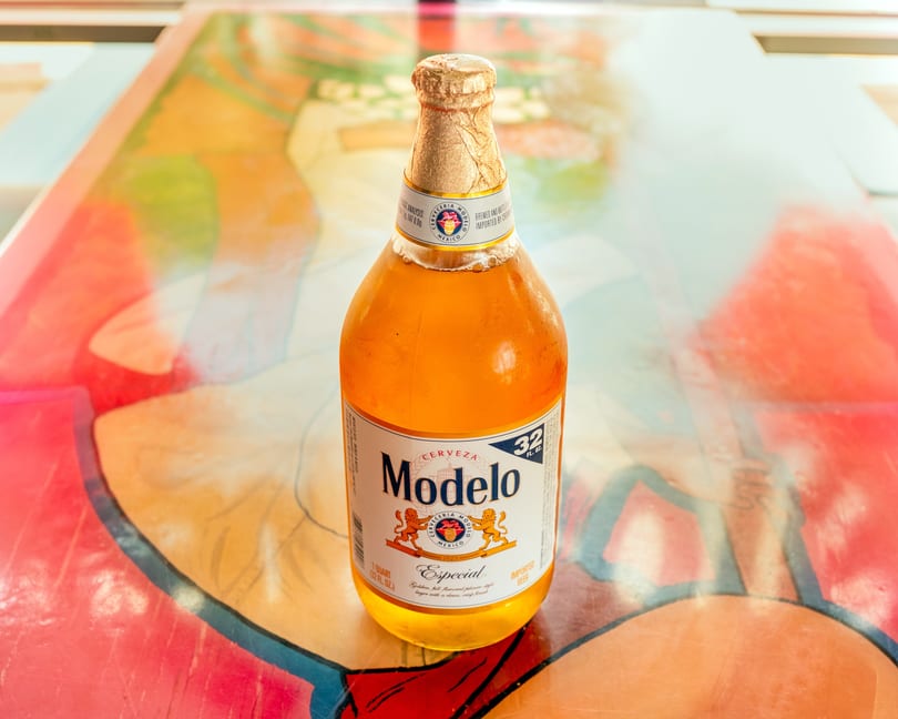 A Modelo Especial beer bottle stands on a colorful, abstract patterned surface.